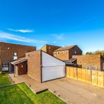 Modern brick house with driveway and blue sky.