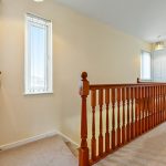 Hallway with wooden bannister and white doors.