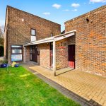 Brick house with paved path and green lawn.