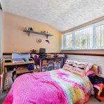 Colourful bedroom with mirrored wardrobe and crafting supplies.