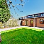 Brick house with garden and trees.