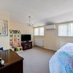 Bright bedroom with TV and dollhouse.