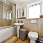 Modern bathroom with shower, sink, and window.