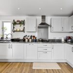 Modern white kitchen with grey countertops.
