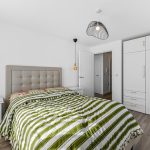 Modern bedroom with striped bedding and white wardrobes.