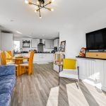 Modern open-plan kitchen and living room with TV.
