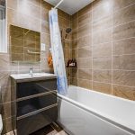 Modern bathroom with tiled walls and bathtub.