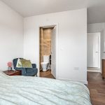 Modern bedroom with en-suite bathroom and wooden furniture.