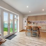 Modern kitchen with garden view through doors.