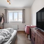 Cosy bedroom with bed, TV, and window view.