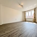 Empty room with wooden floor and large window.