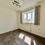 Empty room with wooden floor and bright window.