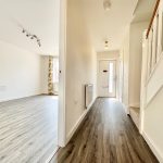 Bright hallway with wooden flooring and stairs.