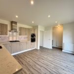 Modern kitchen with wooden cabinets and grey flooring.