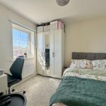 Bright bedroom with bed, wardrobe, desk, and chair
