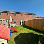 Back garden with slide and brick house.