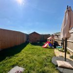 Sunny garden with shed, slide, and playhouse.