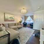 Modern living room with beige sofa and chandelier.