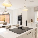 Modern white kitchen with island and dining area.