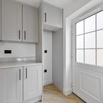 Modern utility room with grey cabinets and window.