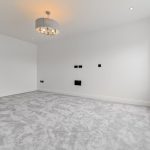 Empty room with grey carpet and modern light fixture.