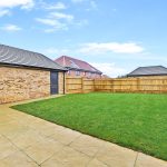Back garden with green lawn and wooden fence.