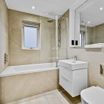 Modern bathroom with bathtub and white sink cabinet.