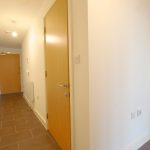 Modern hallway with wooden door and tiled floor.