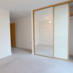 Empty bedroom with mirrored wardrobe and floral wall