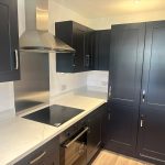 Modern kitchen with dark cabinets and marble countertops.