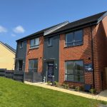 Modern two-storey brick house with garden, blue skies.