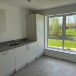 Modern kitchen with large window and white cabinets.