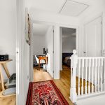 Bright hallway with red carpet, white walls.