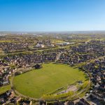 Aerial view of suburban houses and green fields.