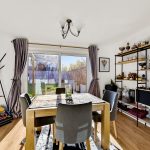 Modern dining room with wooden table and shelves.