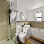Modern bathroom with shower, bathtub, and sink.