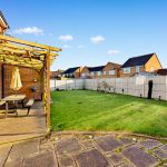 Backyard with wooden deck, table, and fenced lawn.