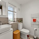Modern bathroom with sink, toilet, and towel rack.