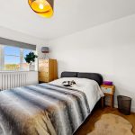 Cosy bedroom with cat on bed.