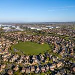Aerial view of suburban houses and green fields.