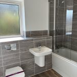 Modern bathroom with shower, sink, and toilet.