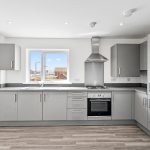 Modern grey kitchen with window and appliances.