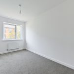 Empty white room with window and grey carpet.
