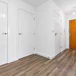 Modern hallway with wooden floor and white doors.