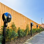 Electric vehicle charging stations along wooden fence.