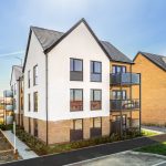Modern brick and white housing development under blue sky.
