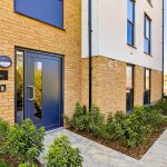 Modern apartment entrance with brick facade and plants.