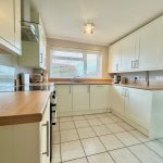 Modern kitchen with white cabinets and tiled floor.