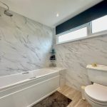 Modern bathroom with marble tiles and bathtub.