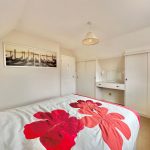 Cosy bedroom with floral bedspread and wall art.